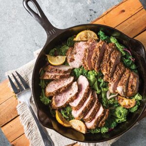 pork tenderloin and veggies in a cast iron skillet