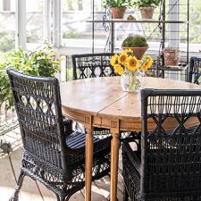 wooden round outdoor table with black wicker chairs