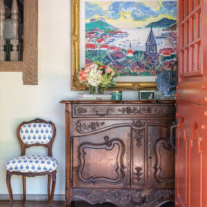 Brown cabinet with painting and blue and white chair