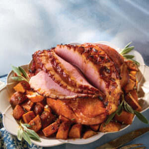 Sliced ham over sweet potatoes in a platter