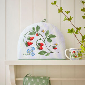 Tea cosy with green vine, blue flowers, and strawberries