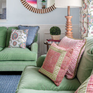 Green couch with pink pillows and blue carpet
