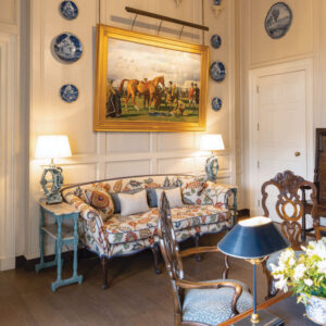 Pattern chair below horse painting with gold frame and blue accent plates