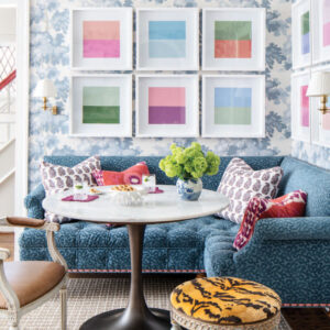Sitting area with round table with blue couch and pink, blue, and green accents