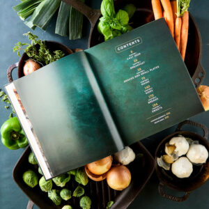 Seasoned styled table of contents surrounded by fresh vegetables