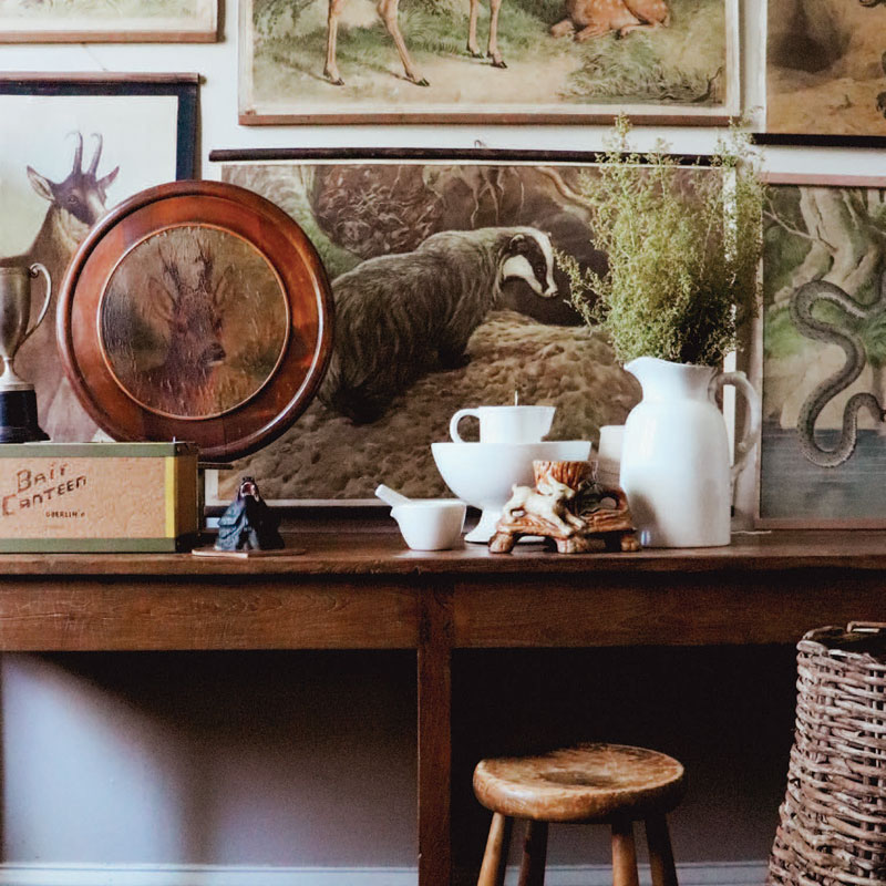 Brown desk with antique globe, white vase, and various wall art