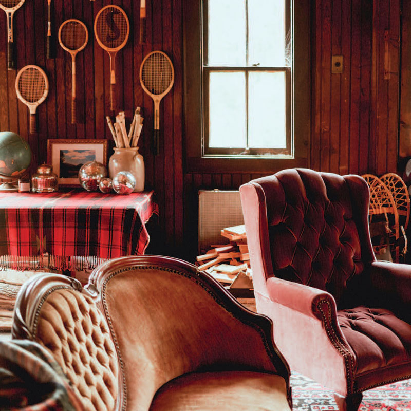 Sitting room with maroon velvet chair and antique racquets on the wall
