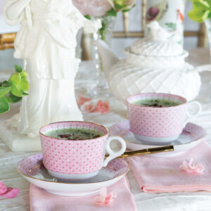 Pink tea cups with tea and white tea pot