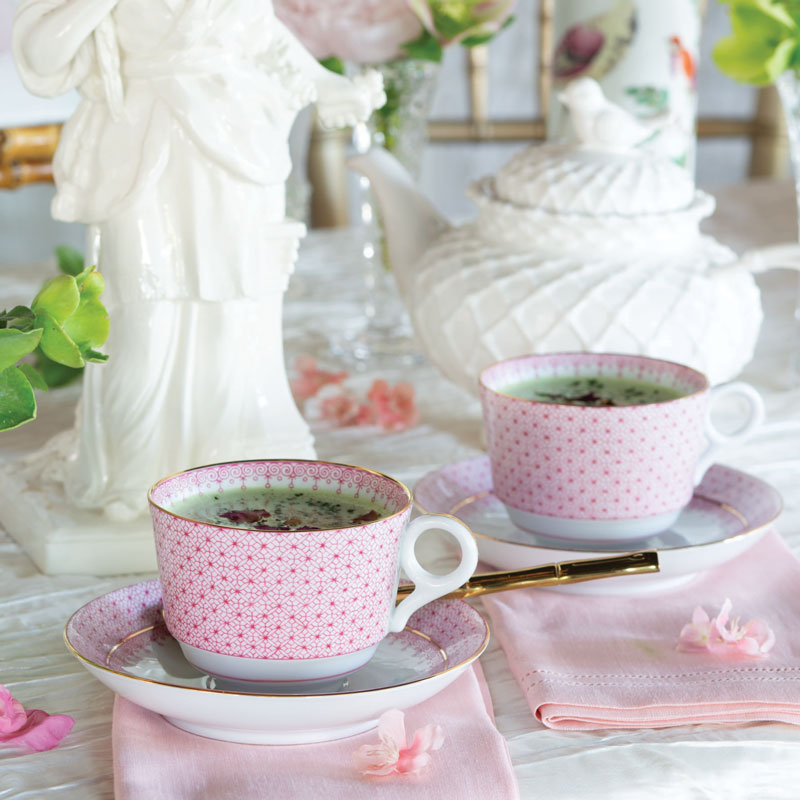Pink tea cups with tea and white tea pot