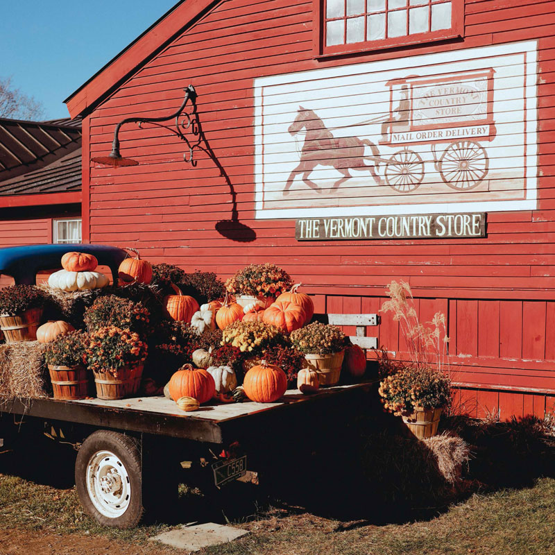 Pumpkins on a truck bed in front of a red barn